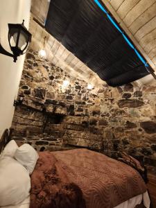 a bedroom with a stone wall with a bed at Atardecer in Tzicuilán