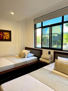 two beds in a room with two windows at Hotel Plaza Mayor 44 in Medellín