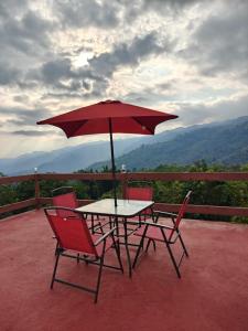 a table and chairs with an umbrella on a patio at Atardecer in Tzicuilán