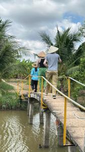 un gruppo di persone che si trovano su un ponte sull'acqua di Nông Trại Hải Vân - Sân Chim Vàm Hồ a Ben Tre