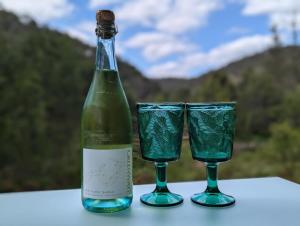 two green glasses sitting next to a bottle of wine at The Burrows Off Grid Cabin, Unplug, Relax & Unwind in Wollombi