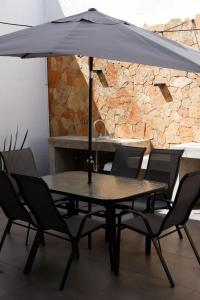 une table noire avec des chaises et un parasol dans l'établissement Modern House with Jacuzzi & Grill 3BR, à La Playita
