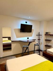 a bedroom with a bed and a desk with a tv at Hotel Plaza Mayor 44 in Medellín
