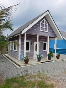 una pequeña casa morada con dos sillas y un porche en Teratak Sumayyah - For Islam Only - Pondok Lenggong, en Kampong Banggol Belimbing