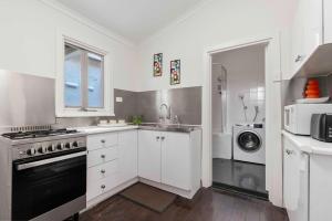 a kitchen with a stove and a sink and a microwave at The Golden Key Henley Beach in Henley Beach South