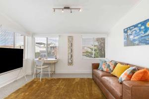 a living room with a couch and a tv at The Golden Key Henley Beach in Henley Beach South