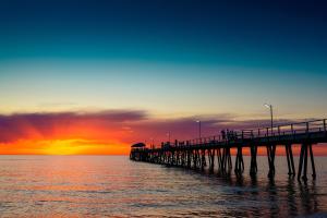 a pier with people on it over the water at sunset at The Golden Key Henley Beach in Henley Beach South