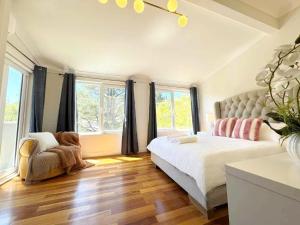 a bedroom with a bed and a chair and windows at Tranquil Suites in Heart of Leura 3 Minutes to Shops in Leura