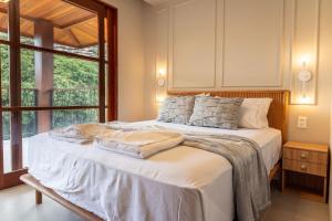 a bedroom with a bed with white sheets and a window at Apartamento Luxuoso com Vista para as Montanhas in Mucugê