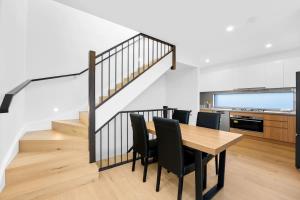 ein Esszimmer mit Tisch und Stühlen und einer Treppe in der Unterkunft Amazing Modern Townhouse at Heart of Mount Waverley in Mount Waverley