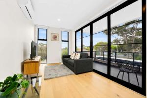 ein Wohnzimmer mit einem Sofa und großen Fenstern in der Unterkunft Amazing Modern Townhouse at Heart of Mount Waverley in Mount Waverley