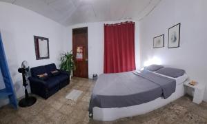 a bedroom with a large bed and a couch at RoomsMagisPalmera in Cahuita