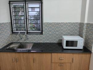 a kitchen counter with a microwave and a sink at ElShium Homes in Cochin +7 photos