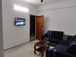 a living room with a couch and a table and a tv at ElShium Homes in Cochin