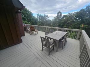 eine Holzterrasse mit einem Tisch und Stühlen darauf in der Unterkunft Luxury Mountain Cabin Rental with a Hot Tub in Helen, Georgia in Helen