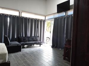 a living room with black curtains and a couch at Pino Longe, Río Celeste in Upala