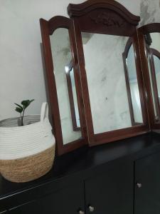 Ein Korb und zwei Spiegel auf einer Kommode mit einer Pflanze in der Unterkunft My Espacinho in São Bento in São Bento do Sul