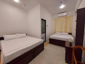 a bedroom with two beds and a desk and a window at Paboda Residency in Minuwangoda