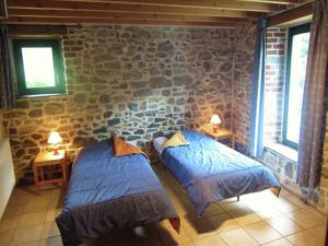 two beds in a room with a stone wall at Apartment near Forest and Hiking Trails in Treignes