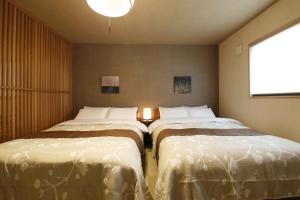 two beds in a small room with a window at Kamon Inn Uji 2-D in Uji
