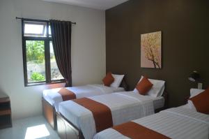 a hotel room with three beds and a window at Pondok Ganda in Ambarita +208 photos