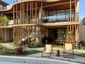 deux chaises assises devant un bâtiment dans l'établissement Flat premium no Naay Villas Boutique para 8 pessoas, à Tatuamunha