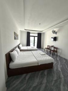 une chambre d'hôtel avec deux lits et une table dans l'établissement Hotel Bảo Bảo, à Thuan An 3 autres photos