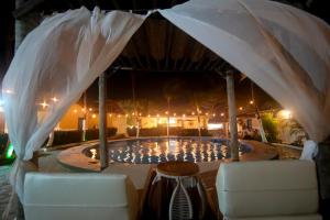 a swimming pool at night with two chairs and an umbrella at Pousada Hippopotamus Jeri in Jericoacoara