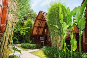 a garden with a wooden house with plants at Kubu Kak Dudung Villas in Jimbaran