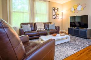 a living room with a leather couch and a tv at Westcott 3 Bed Apt in Mansion mins to SU JMA Dome in Syracuse