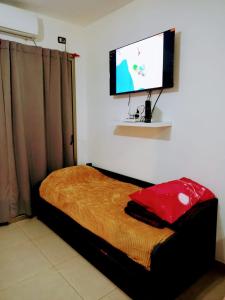 a bedroom with a bed with a flat screen tv on the wall at Bonaires V departamento monoambiente cerca de la costanera in Corrientes
