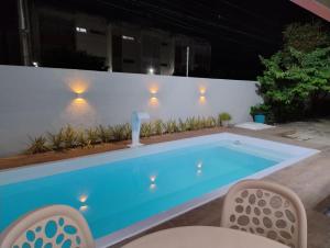 ein Pool in der Nacht mit Lichtern an einer weißen Wand in der Unterkunft Casa em Olinda com piscina para o carnaval in Olinda + 7 Fotos