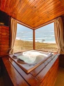 a bath tub in a room with a large window at Pousada Invernada in São Joaquim