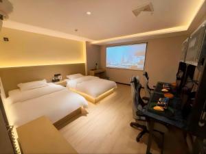 a hotel room with two beds and a desk and a television at Hulk Esports Cinema Hotel Guiyang Fountain Pool Branch in Guiyang