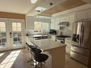 a kitchen with white cabinets and a island with bar stools at South OC House in Laguna Niguel