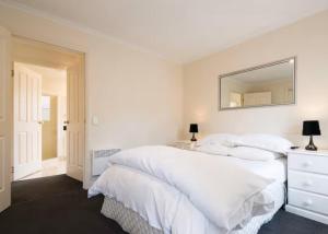 a white bedroom with two beds and a mirror at Kingston apartment in Kingston