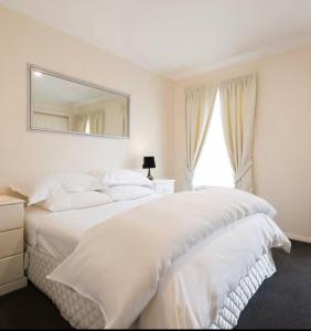 a white bedroom with two beds and a mirror at Kingston apartment in Kingston