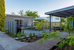 einen Garten mit einem Tisch und einem Sonnenschirm in der Unterkunft Memories - stunning relaxation near lake with private hot tub in Taupo Airport