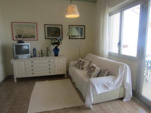 sala de estar con sofá blanco y TV en Appartamento mare mare, en Forza dʼAgro