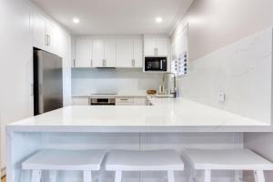 バッセルトンにあるOpal Laneの白いキャビネットと白いスツール付きの白いキッチン