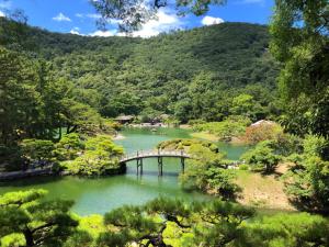 eine Brücke über einen See in einem Wald in der Unterkunft ゲストハウスsimasima古馬場301 in Takamatsu