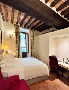 a bedroom with a large white bed and a desk at Grand Hotel Continental Siena - Starhotels Collezione in Siena