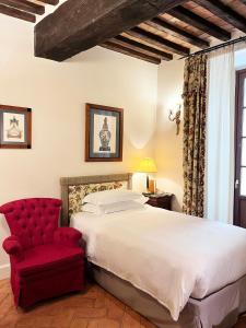 a bedroom with a bed and a red chair at Grand Hotel Continental Siena - Starhotels Collezione in Siena