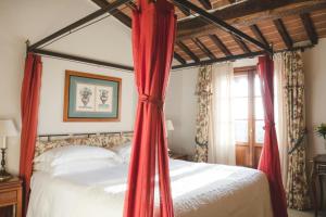 a bedroom with a canopy bed with red curtains at Grand Hotel Continental Siena - Starhotels Collezione in Siena