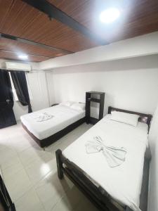 two twin beds in a room with white sheets at Hotel Coralite Suites Lions in Santa Marta