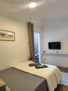a bedroom with a bed and a flat screen tv at Suíte privativa Vila Dom Pedro in Paraty