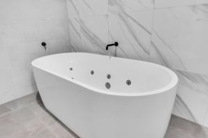 a white bath tub in a white bathroom at The Palms Apartments in Merimbula