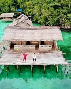 zwei Menschen stehen auf einem Pier im Wasser in der Unterkunft Full Board Raja Ampat Sanara Homestay in Waisai