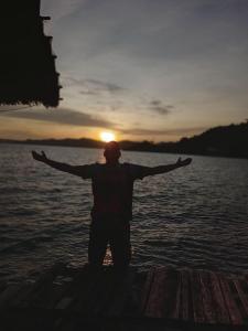 Ein Mann steht im Wasser mit ausgestreckten Armen in der Unterkunft Full Board Raja Ampat Sanara Homestay in Waisai