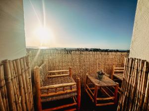 two chairs and a table on a balcony with the sun at Superbe Appartement avec vue paronamique sur la plage Achakar - proche de Cap Spartel - Grottes Hercule N2 in Tangier